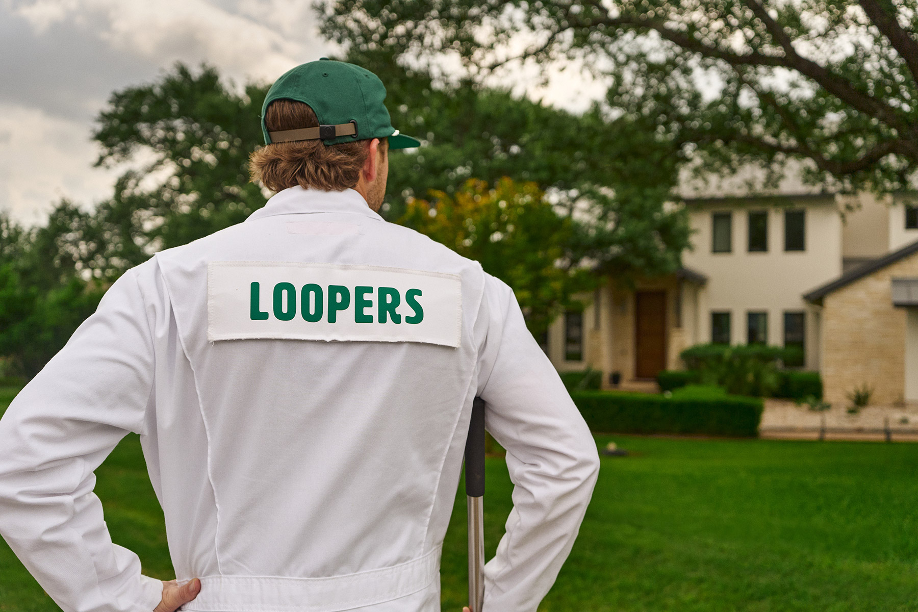 Loopers lawn care tech inspecting green grass